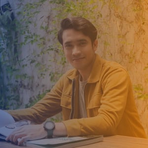 Early 30s Asian man sat at table wearing a yellow jacket