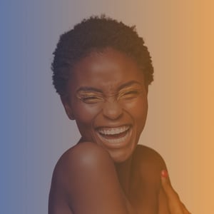Early 30s black woman with short hair laughing while hugging her shoulders