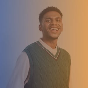 Mid 20s smiling black man wearing a green tank top over a white shirt