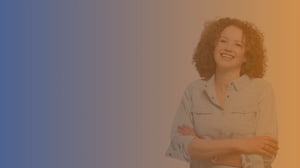 Mid 40s smiling white woman with red hair wearing a light blue shirt with arms crossed